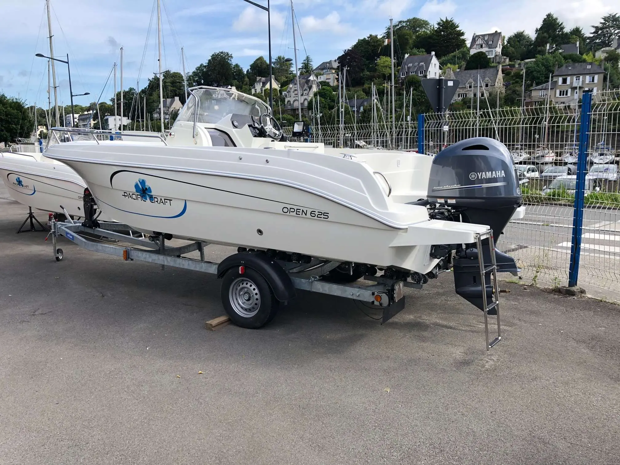 Pacific Craft 625 Open — Bateau à moteur blanc vu de trois quarts arrière, posé sur une remorque.