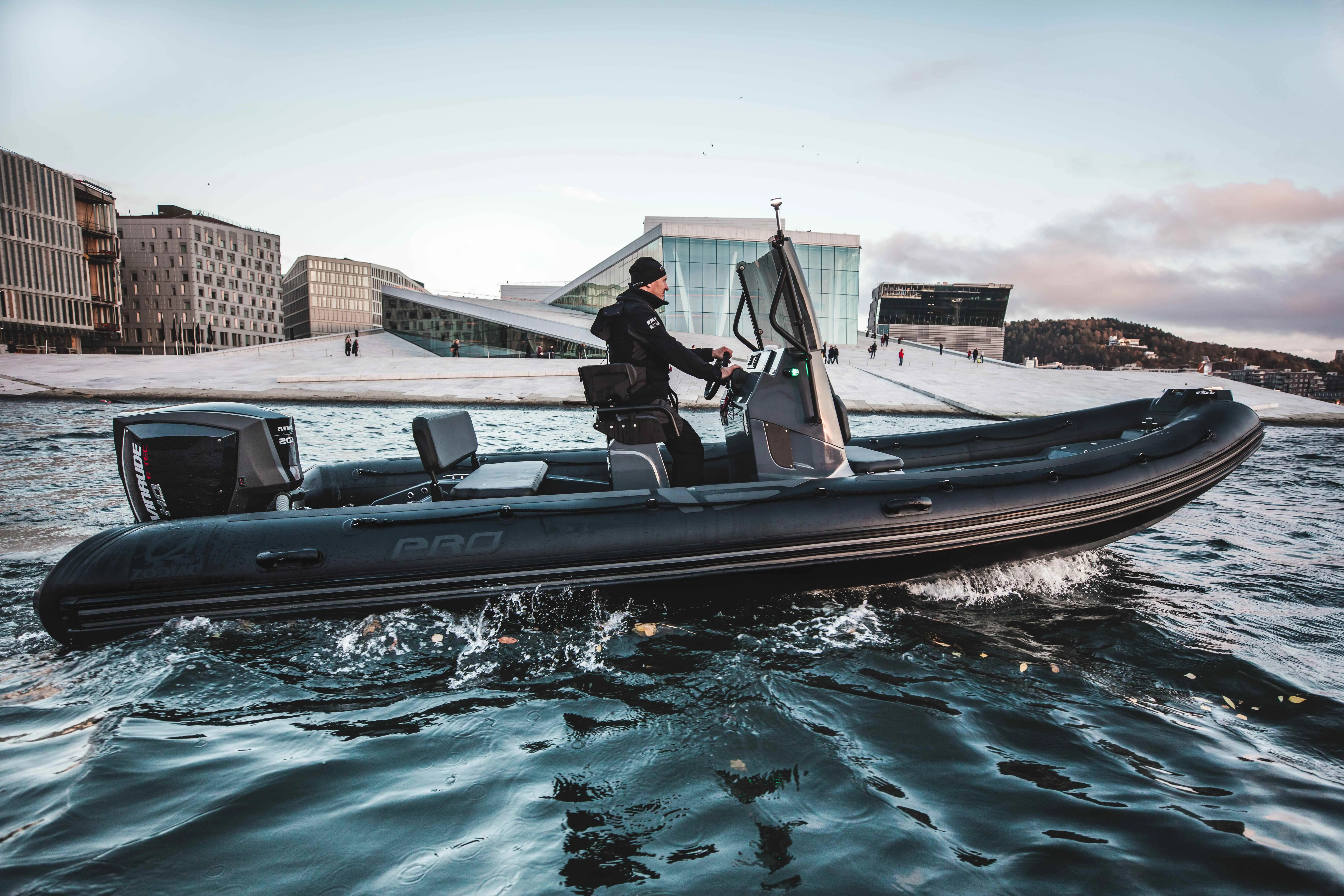 Zodiac Pro 7 — Bateau pneumatique à moteur hors-bord naviguant devant un front de mer enneigé.