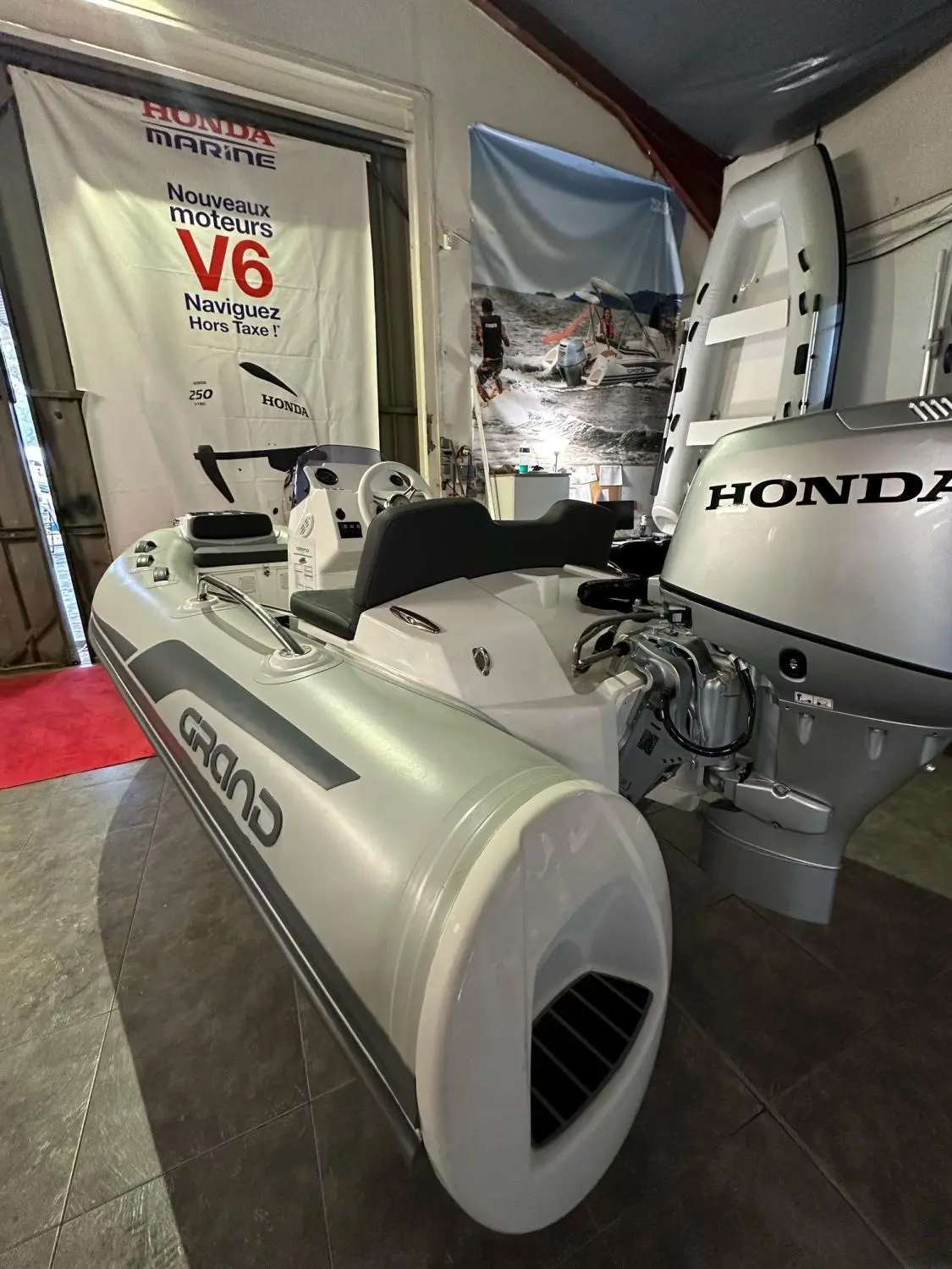 Grand Golden Line G340 — Bateau pneumatique Grand exposé en intérieur avec un moteur hors-bord Honda.