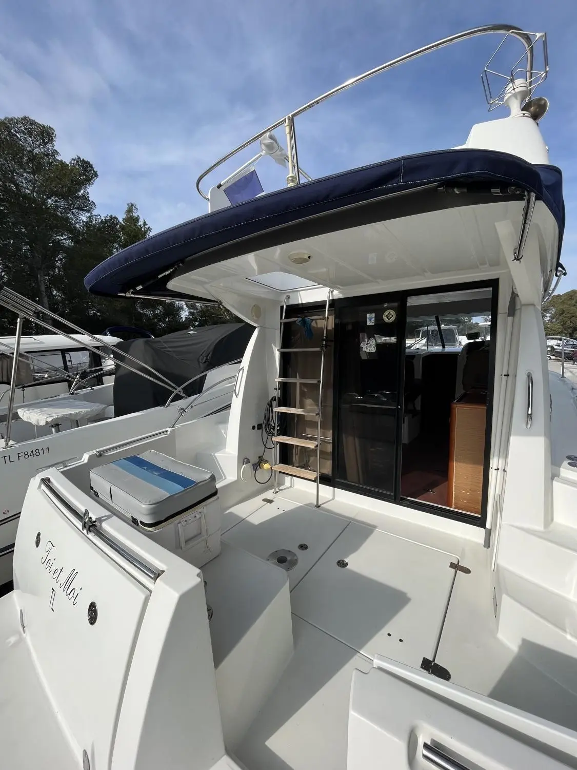 Jeanneau Merry Fisher 10 — Vue du cockpit arrière et de l'accès intérieur d'un bateau à moteur amarré.