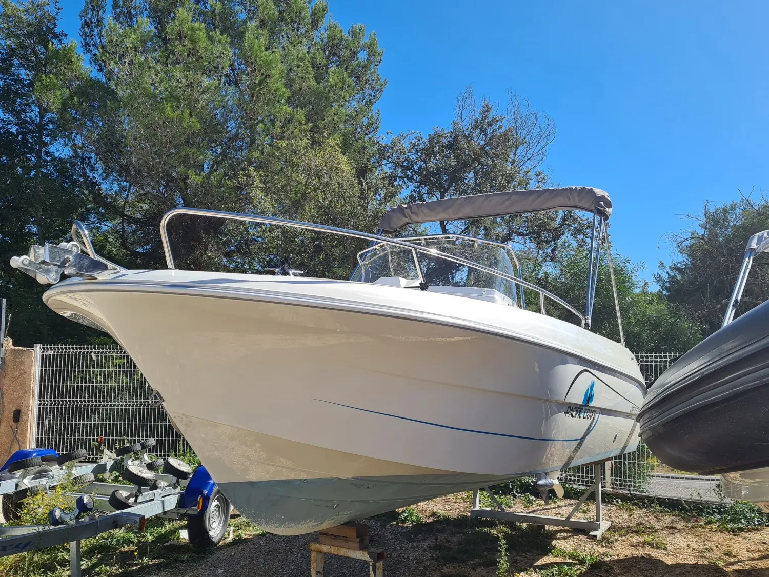 Pacific Craft 545 Trendy — Bateau à moteur blanc vu de trois quarts avant, posé sur une remorque.
