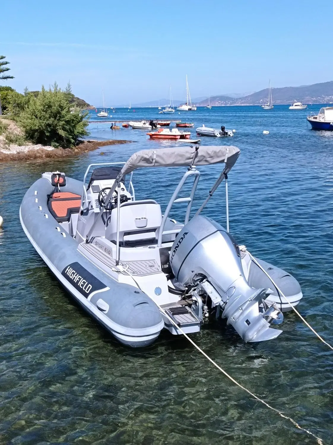 Highfield Sport Range 650 — Bateau semi-rigide gris et blanc amarré dans une baie, avec moteur hors-bord.