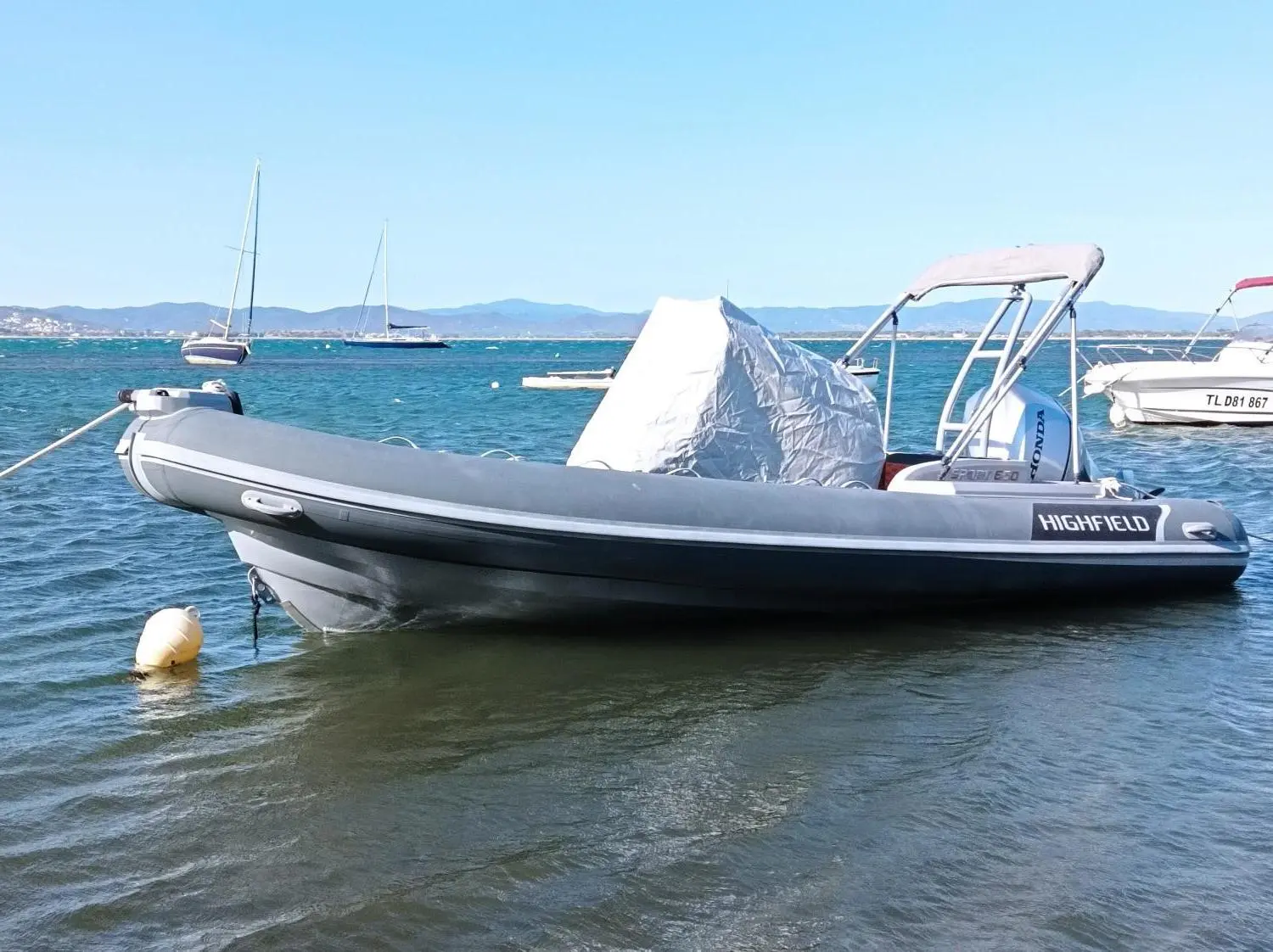 Highfield Sport Range 650 — Bateau pneumatique gris amarré dans une baie, vu de profil sur l’eau.