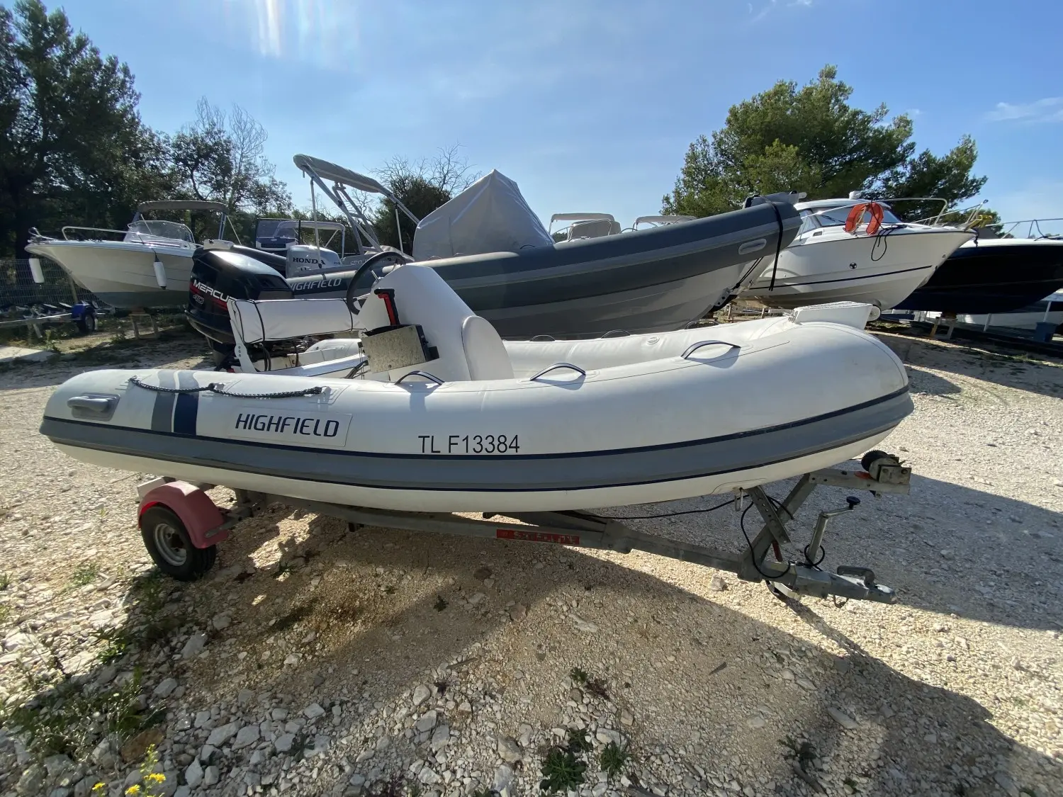 Highfield OM 350 T — Bateau pneumatique blanc sur remorque, photographié de trois quarts dans un parc nautique.