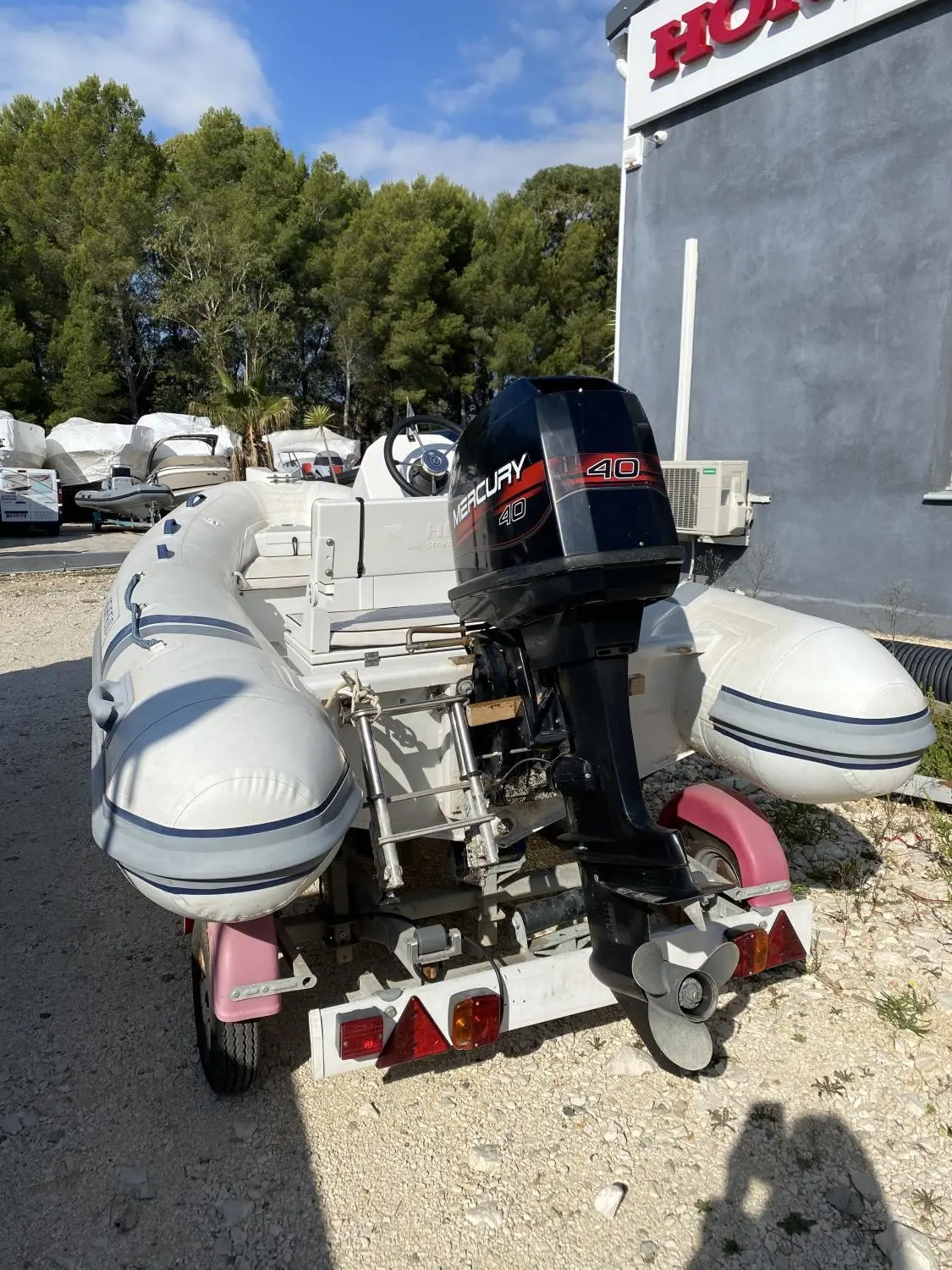 Highfield OM 350 T — Vue arrière d’un bateau pneumatique blanc équipé d’un moteur hors-bord sur remorque.