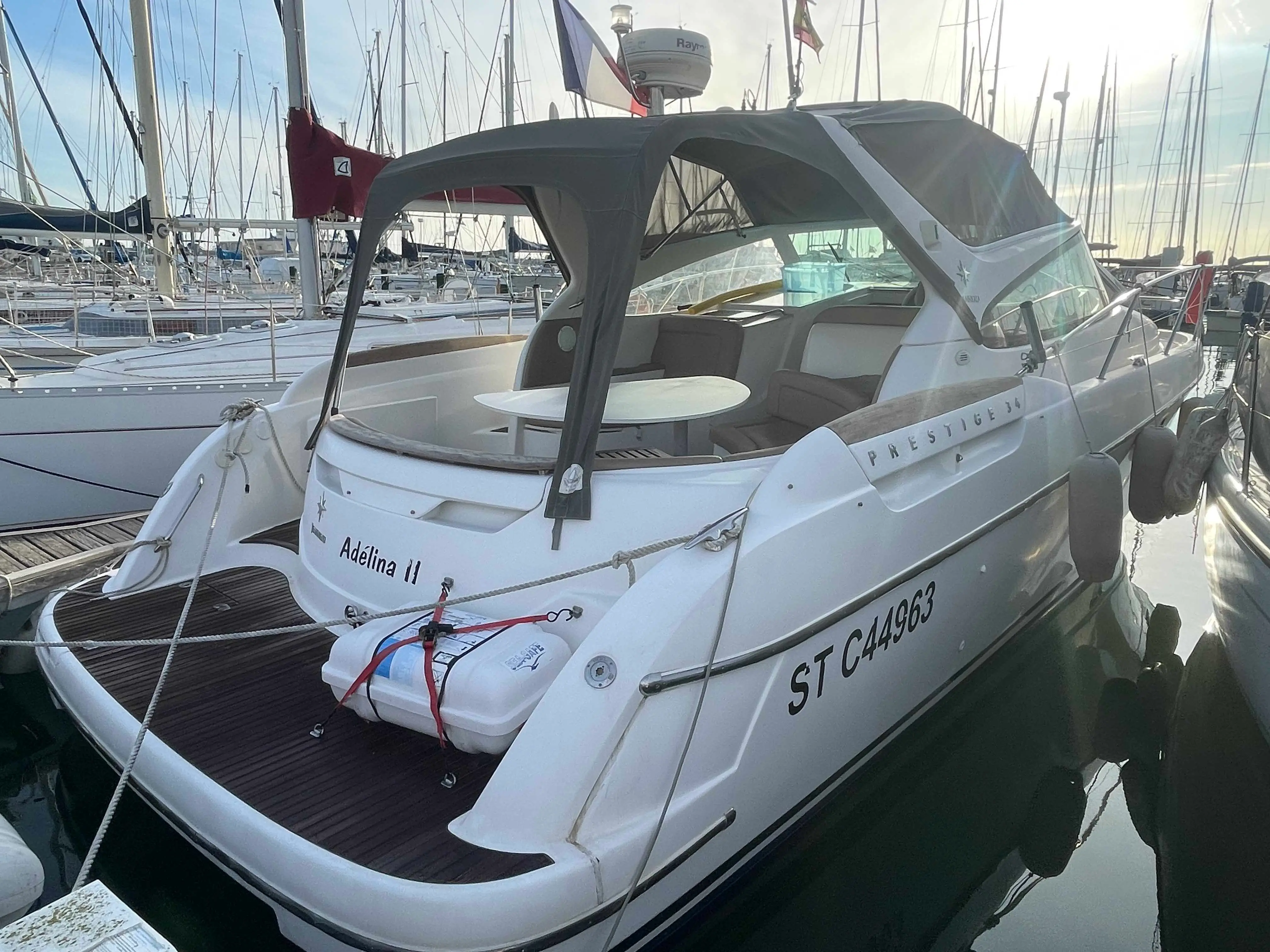 Jeanneau Prestige 34 — Bateau à moteur blanc vu de trois-quarts arrière dans une marina.