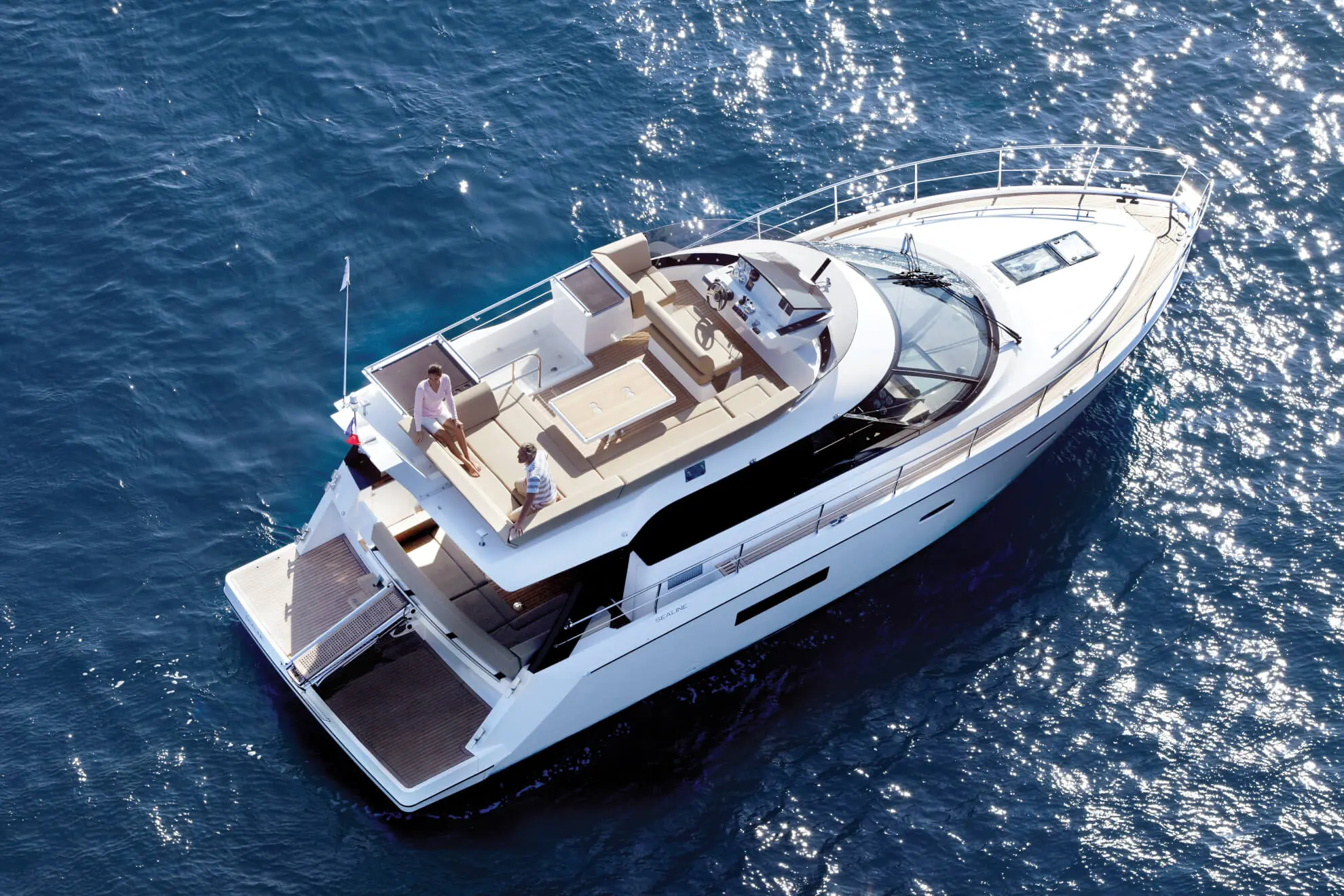 Sealine F 42 — Vue aérienne d’un yacht blanc sur une mer scintillante, avec deux personnes à bord.