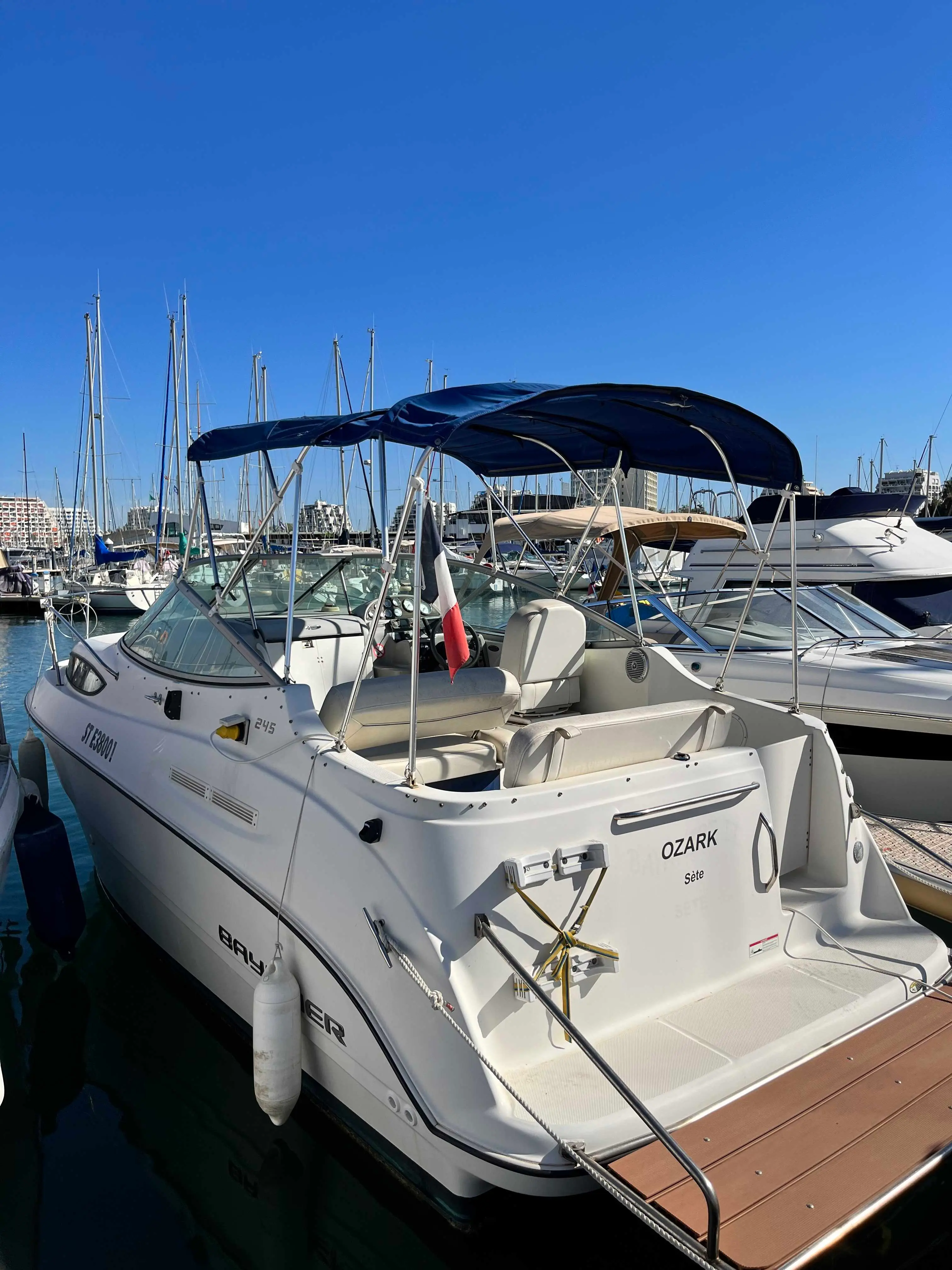 Bayliner 245 — Bateau à moteur blanc amarré dans un port, vu depuis l’arrière bâbord.