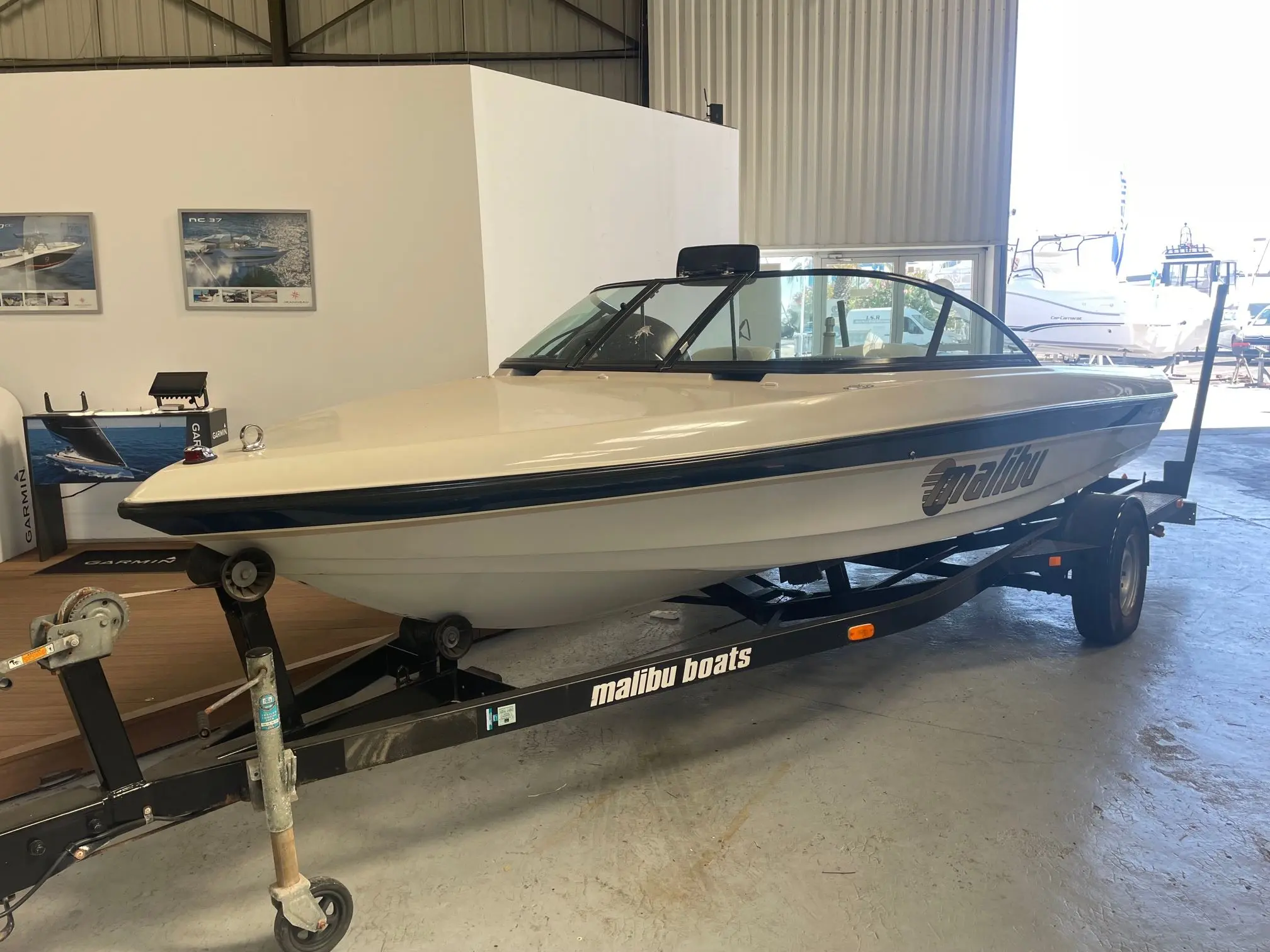 Malibu Response — Bateau à moteur présenté sur sa remorque dans un showroom nautique.