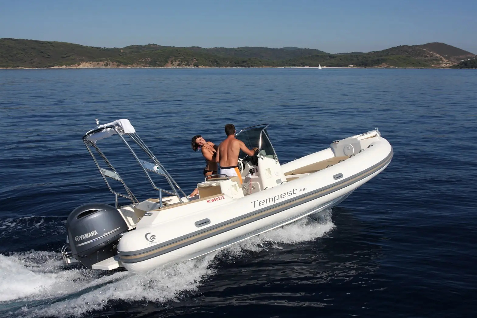 Capelli Tempest 700 — Un semi-rigide blanc navigue au large avec deux personnes à bord.