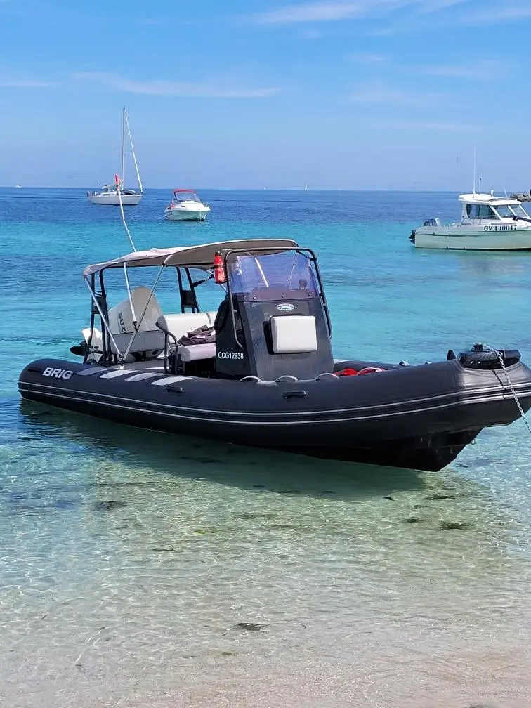 Brig Navigator 610 — Bateau semi-rigide noir amarré dans une eau turquoise, vu de trois quarts.