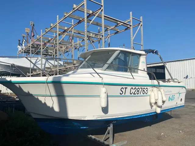 Ocqueteau 645 — Bateau à moteur blanc vu de trois quarts, stationné à terre.