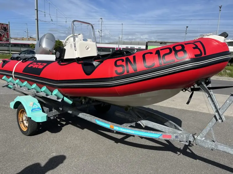 Zodiac Pro 7 Man — Bateau pneumatique rouge équipé d’un moteur hors-bord et posé sur une remorque.