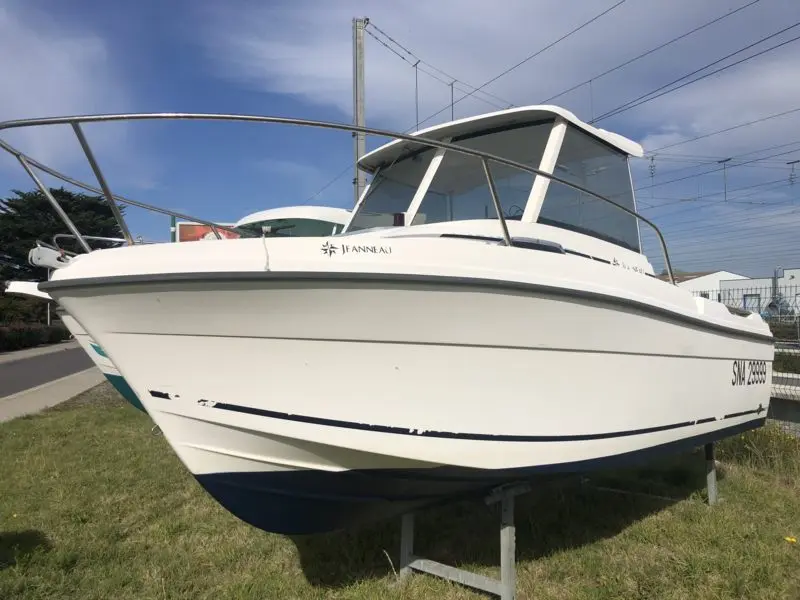 Jeanneau Merry Fisher 580 — Bateau à moteur blanc vu de trois quarts avant, exposé à terre.