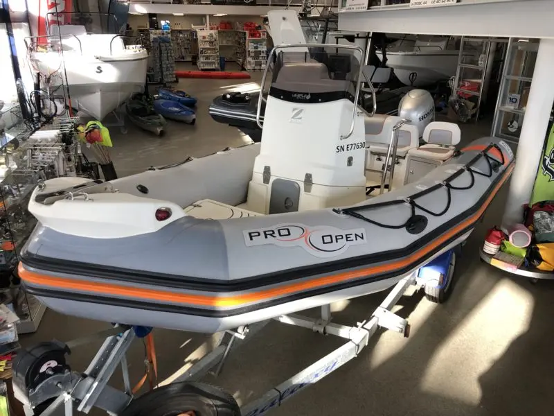 Zodiac Pro Open 550 — Bateau pneumatique gris et orange présenté sur sa remorque en magasin nautique.