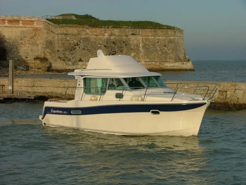 Ocqueteau 975 — Bateau à moteur blanc et bleu photographié de trois quarts dans un port.