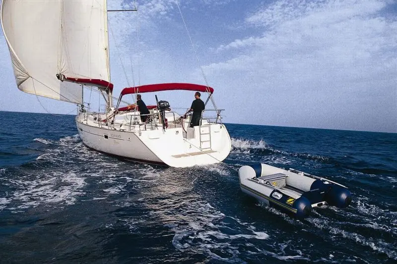 Zodiac Cadet 200 — Un voilier blanc navigue devant une annexe semi-rigide en mer.