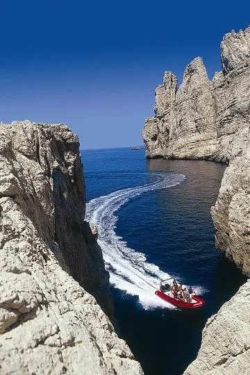 Zodiac Pro 15 Man — Bateau semi-rigide rouge naviguant entre des falaises côtières.