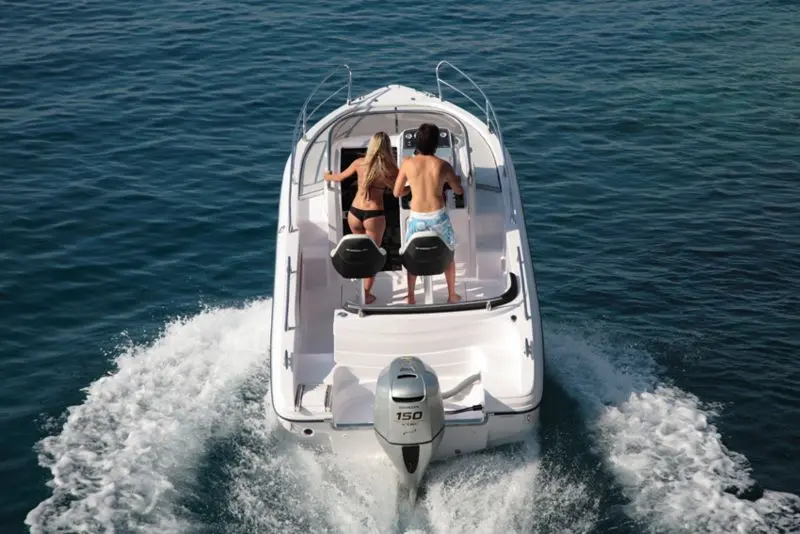 Ranieri Shadow 20 — Vue arrière d’un bateau à moteur blanc naviguant sur l’eau, avec deux personnes à bord.
