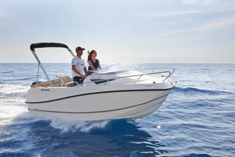 Quicksilver Activ 455 Cabin — Bateau à moteur blanc naviguant en mer avec deux personnes à bord.
