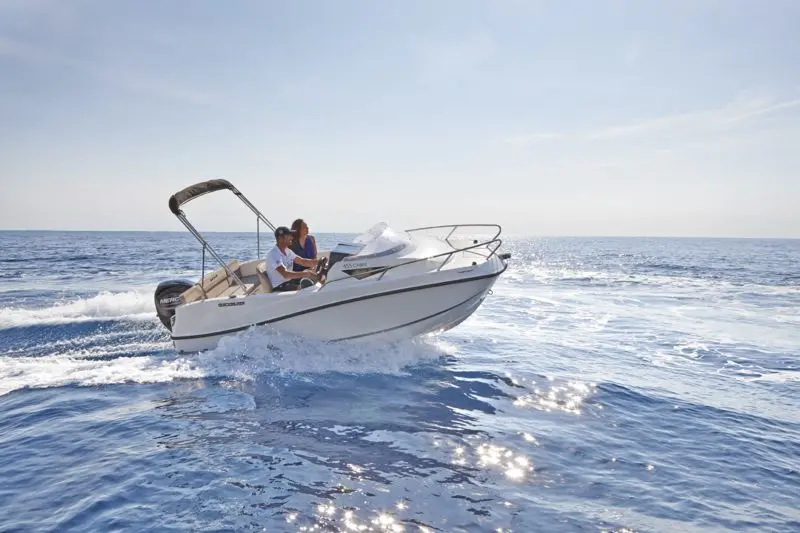 Quicksilver Activ 455 Cabin — Bateau à moteur blanc naviguant en mer avec deux personnes à bord.