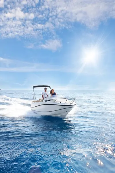 Quicksilver Activ 455 Cabin — Bateau à moteur naviguant en mer, vu de trois quarts avant, avec deux personnes à bord.