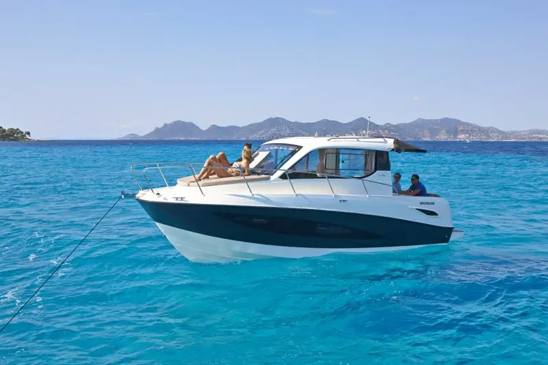 Quicksilver 855 Cruiser — Bateau à cabine blanche et coque sombre au mouillage sur une mer turquoise.