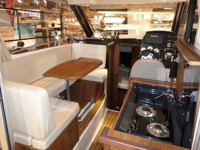 Quicksilver 855 Cruiser — Vue intérieure d’un bateau montrant le carré, la cuisine et le poste de pilotage.