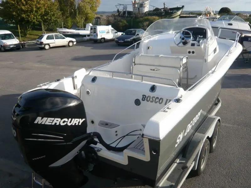 Kelt White Shark 248 — Bateau à moteur blanc et gris présenté sur sa remorque, vu de trois quarts arrière.