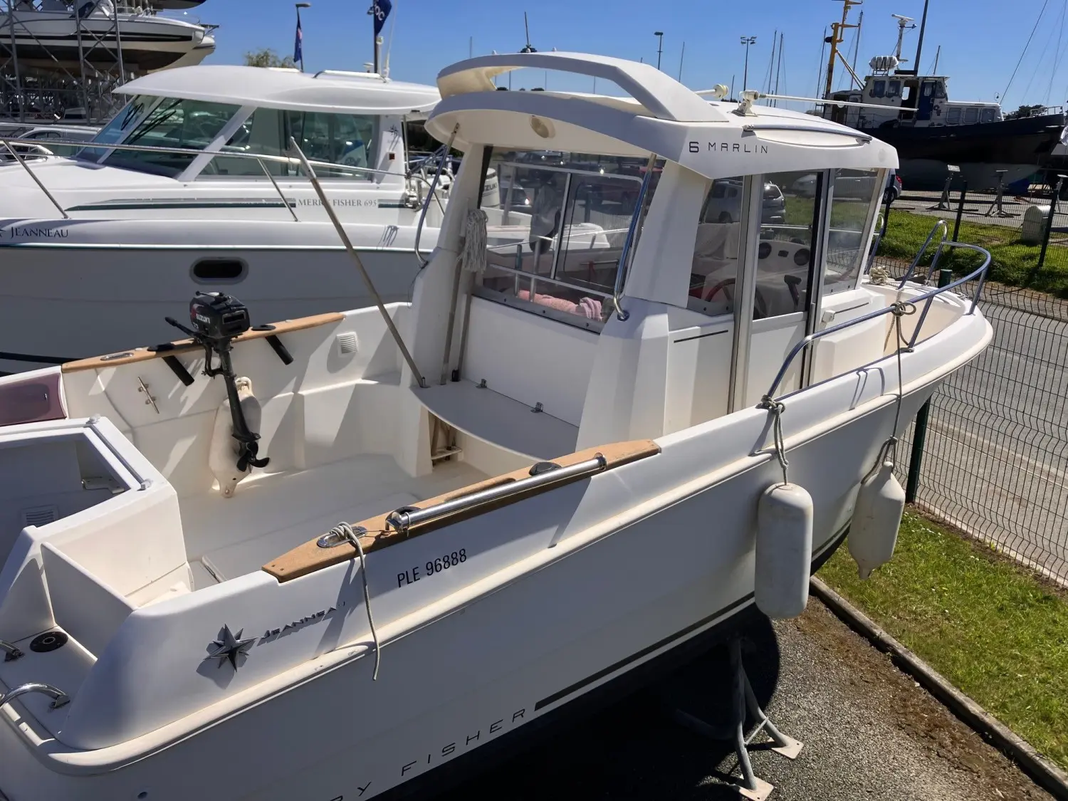 Jeanneau Merry Fisher 6 Marlin — Vue trois quarts d’un bateau blanc à cabine, exposé à terre dans un chantier nautique.