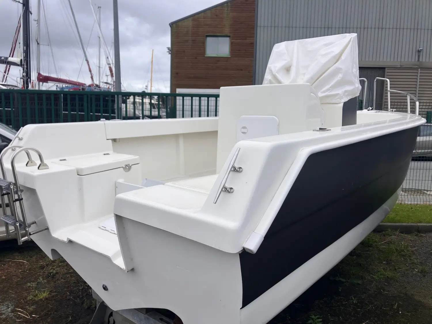 Acroplast Albacore — Vue arrière trois-quarts d’un bateau blanc et bleu stationné à terre.