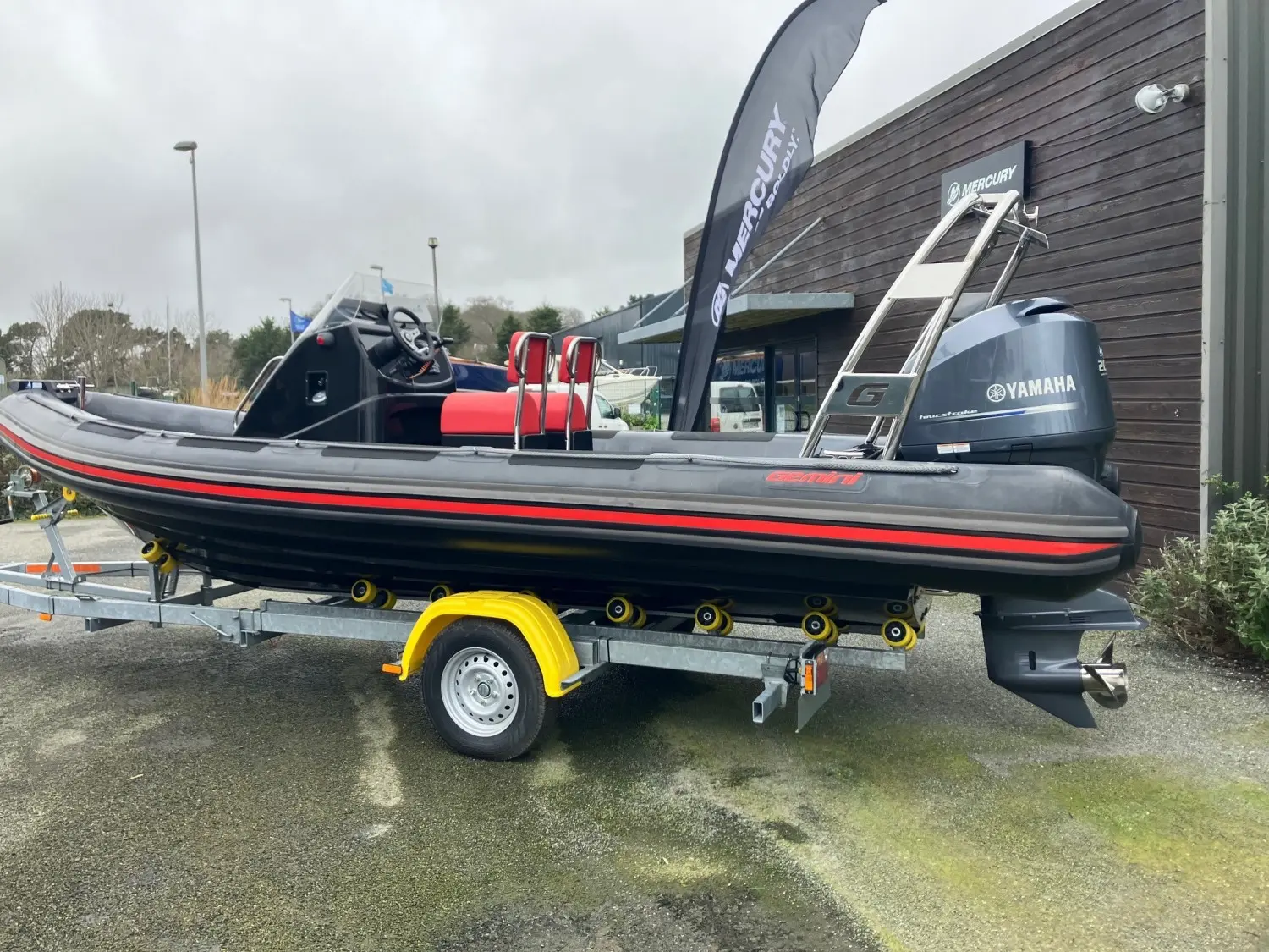Gemini Waverider 650 — Bateau pneumatique à moteur hors-bord présenté sur sa remorque devant un bâtiment.