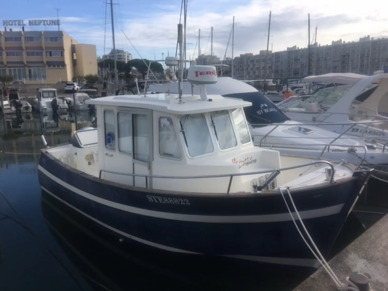 Rhea 730 Fishing — Bateau à cabine amarré dans un port, entouré d'autres embarcations.