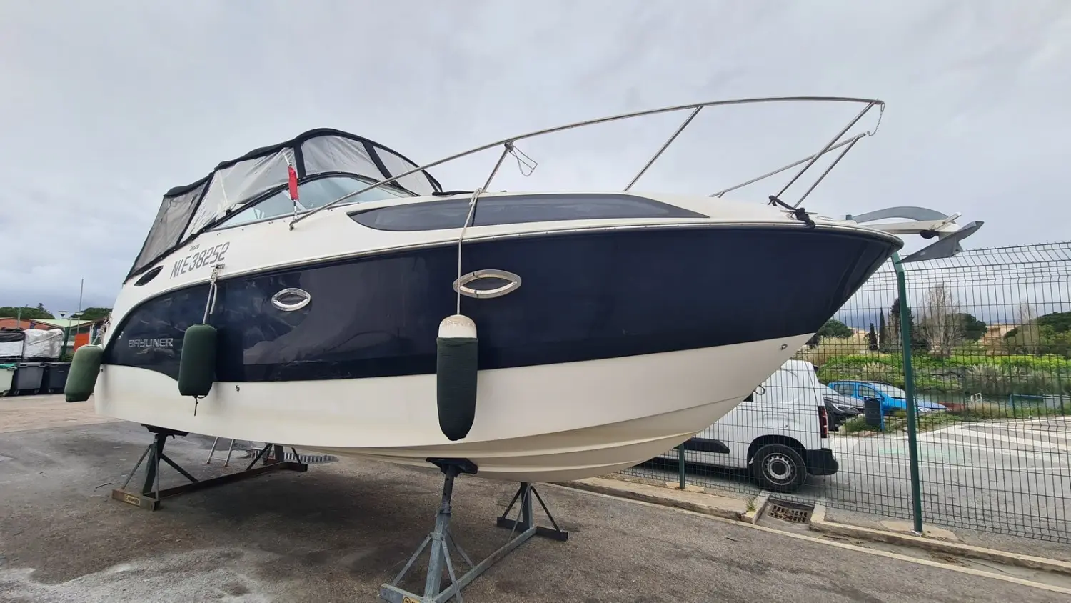 Bayliner 255 — Bateau à moteur blanc et bleu présenté sur sa remorque dans une cour extérieure.