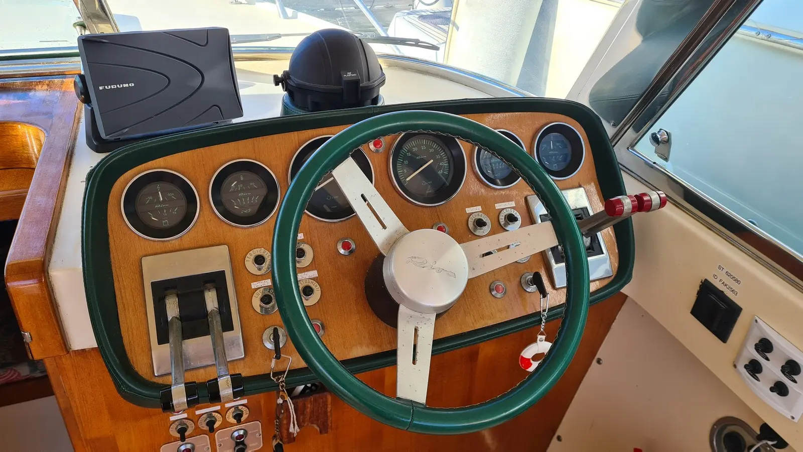 Riva 25 Sport Fisherman — Poste de pilotage en bois avec volant, instruments et commandes du bateau.