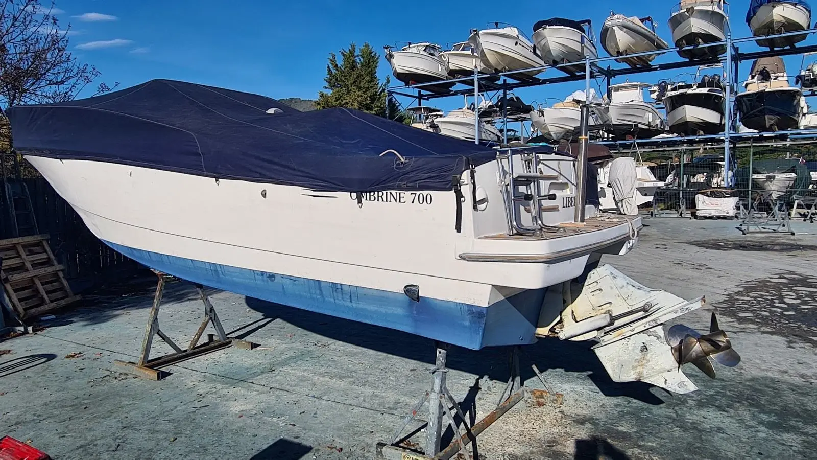 Beneteau Ombrine 700 — Bateau à moteur bâché, hors de l’eau sur bers, photographié dans un chantier nautique.
