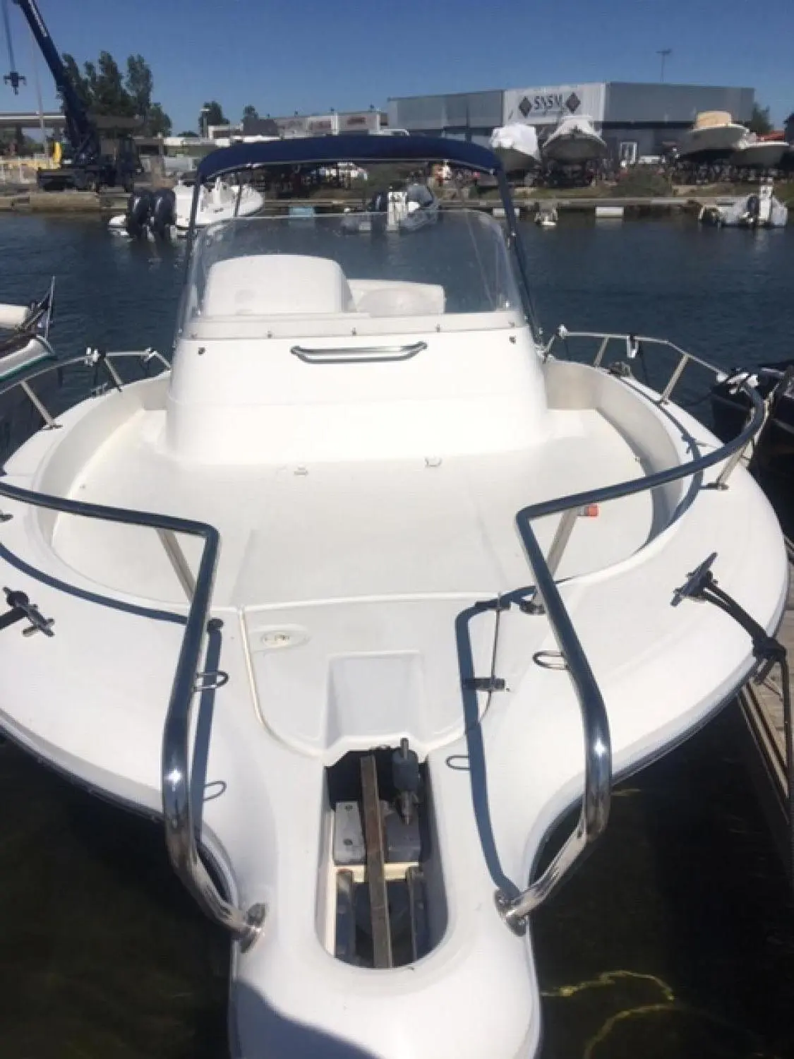 White Shark 248 — Vue avant d’un bateau blanc amarré, avec console centrale et pare-brise.