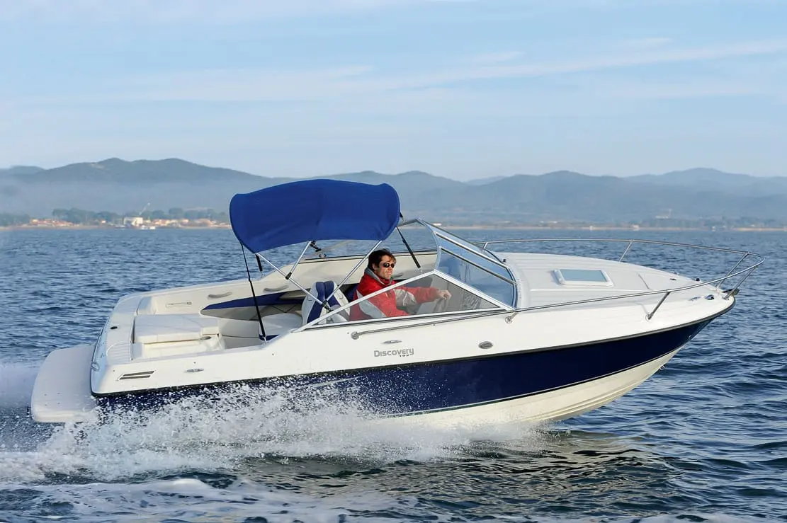 Bayliner 192 Discovery — Bateau à moteur blanc et bleu naviguant sur l’eau avec une personne à la barre.