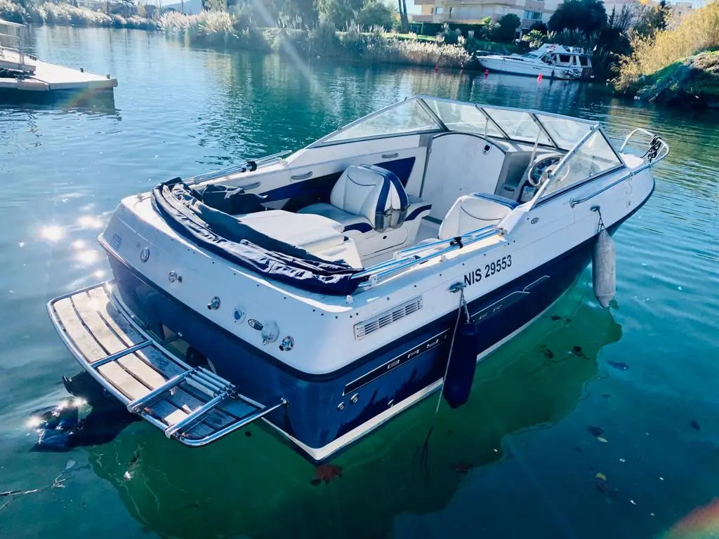Bayliner 192 Discovery — Bateau à moteur blanc et bleu vu de trois quarts arrière sur une eau calme.