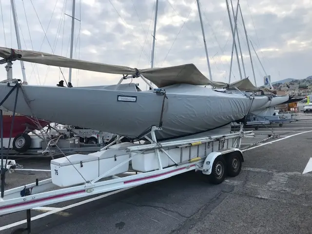 Petticrows Dragon — Voilier gris bâché posé sur une remorque dans un port.