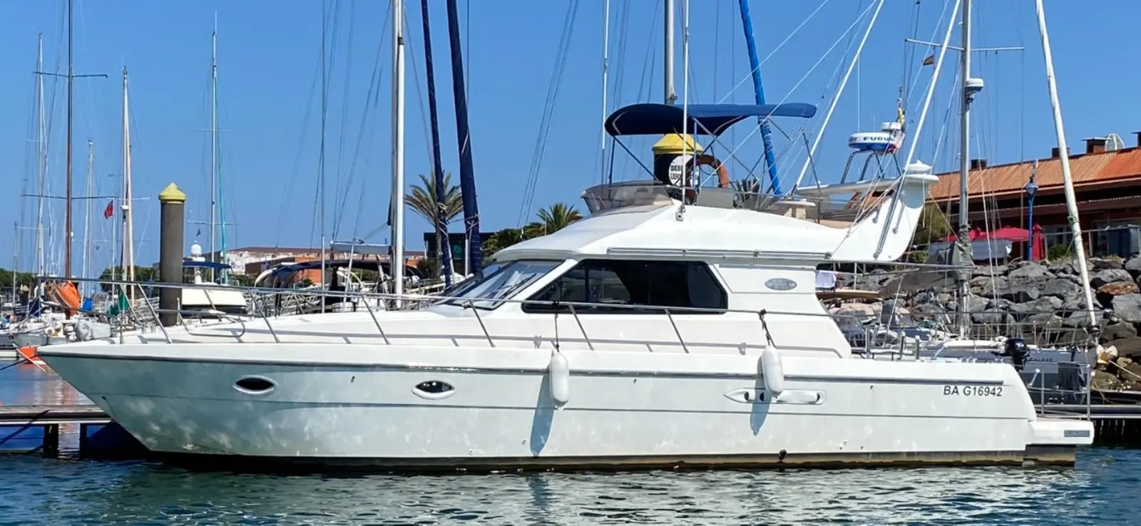 Doqueve 410 — Bateau à moteur blanc vu de profil, amarré dans un port sous un ciel dégagé.