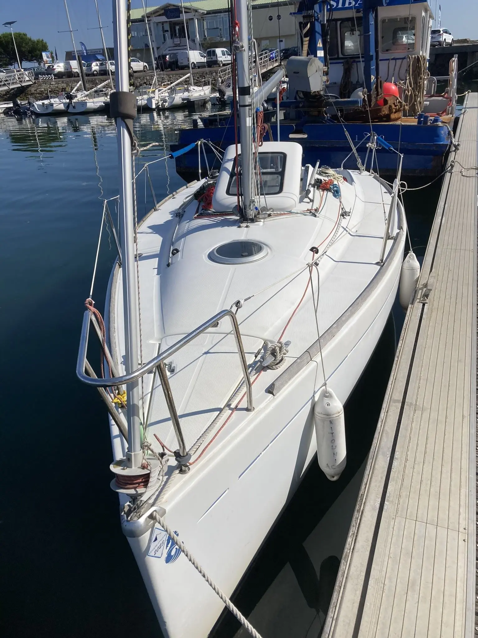 Beneteau First 211 — Voilier blanc amarré au ponton, photographié depuis l'avant tribord.